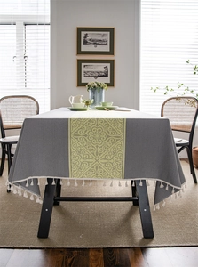 Detailed view of dark grey tablecloth with yellow jacquard pattern and white tassels
