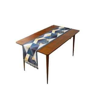 Modern luxury geometric jacquard table runner with golden tassels on a dark wood table