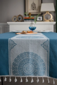 Close-up of blue jacquard sunflower tablecloth with white tassels and boho patterns