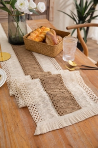 Detail of rustic cotton linen table runner with woven stripes, crochet texture and fringe