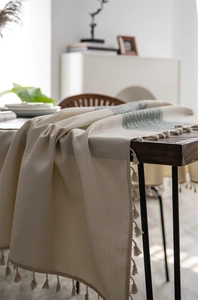 Detailed close-up of woven geometric diamond pattern and fringe edge on the tablecloth