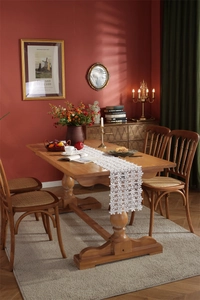 Macro detail of white hollow floral lace table runner on a rustic wooden dining table