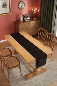 Detail of black lace table runner with intricate floral patterns on a wooden dining table