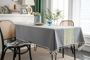 Detail of grey tablecloth featuring yellow leaf pattern and elegant white tassel trim
