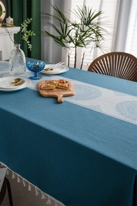Detail of blue jacquard tablecloth featuring white mandala patterns and fringe edges