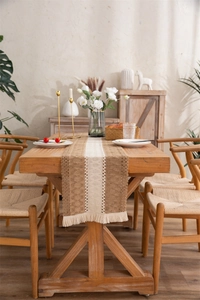 Macro detail of natural cotton linen table runner with crochet lace and tassel fringe