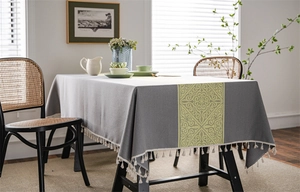 Close-up of grey jacquard tablecloth with yellow geometric patterns and cotton fringes