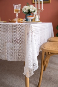 Detailed view of off-white lace tablecloth with geometric patterns and fringe detail