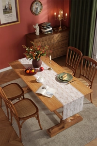 Detail of white rose lace table runner featuring delicate floral embroidery and scalloped edges