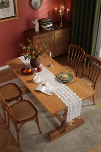 Detailed embroidery view of romantic white hollow lace table runner on wooden table