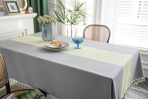 Detail of grey jacquard tablecloth featuring floral patterns and white fringe tassels