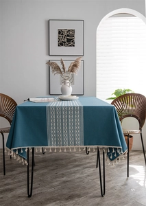 Close-up of teal jacquard tablecloth featuring white geometric patterns and tassel fringe detail
