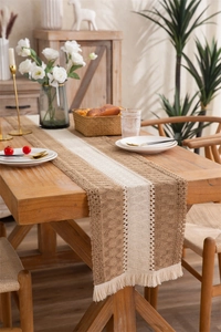 Detail view of woven table runner with tassel edges and striped pattern on wooden surface