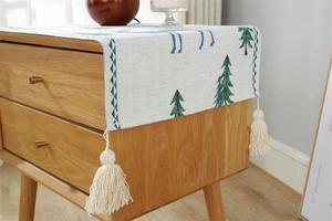 Close-up of jacquard dust cover featuring forest motifs and handmade fringe tassels