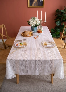 Close-up detail of cream lace tablecloth with intricate geometric cutout patterns