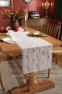 Close-up of white lace table runner featuring romantic rose patterns and scalloped edges