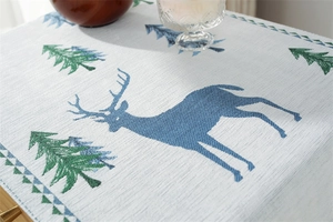 Macro shot of thick woven jacquard fabric with blue reindeer and green pine tree patterns