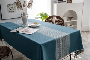 Detailed macro view of navy blue jacquard table cloth with geometric patterns and beige tassels