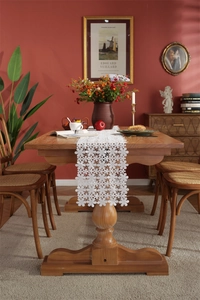 Close-up of white floral hollow lace table runner on a vintage wooden dining table