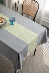 Detail view of dark grey leaf pattern tablecloth featuring elegant white tassel fringes