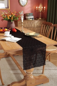 Detail of black floral lace table runner with hollow-out pattern on wooden table