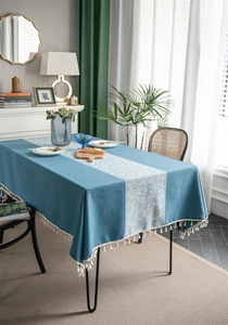 Close-up of teal blue jacquard tablecloth with white lace floral center and tassel fringe