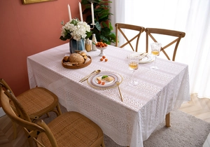 Close-up of beige French lace tablecloth with hollow floral pattern and cotton texture