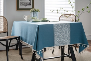 Detailed view of dark blue jacquard tablecloth featuring classic patterns and tassel edges