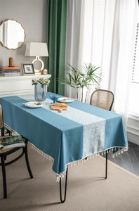 Detail of blue rectangular tablecloth featuring white sunflower jacquard and tassel edges