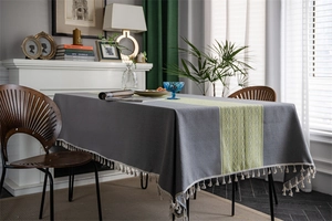 Detailed close-up of gray table cloth featuring geometric woven trim and white fringe tassels