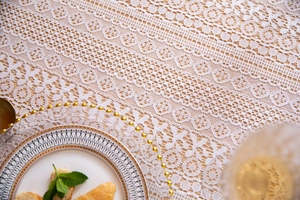 Close-up of elegant French lace tablecloth with intricate floral cutouts and patterns