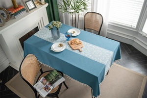 Detail of peacock blue rectangular tablecloth with white floral lace and fringe trim