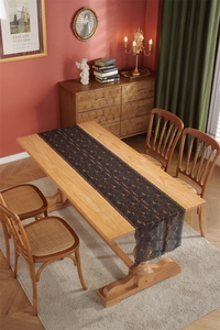 Detail of elegant black lace table runner with rose patterns on a vintage wooden dining table