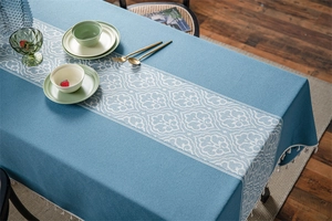 Detail of navy jacquard tablecloth featuring white scroll patterns and elegant fringe tassels