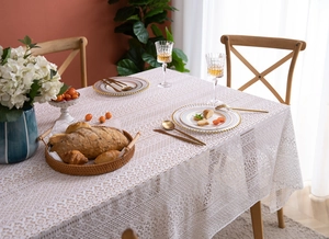 Detail of elegant cream floral lace tablecloth with intricate hollow cutouts on dining table
