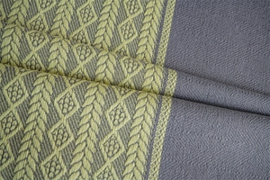 Close-up of grey and lime green jacquard fabric featuring geometric leaf patterns and fringe