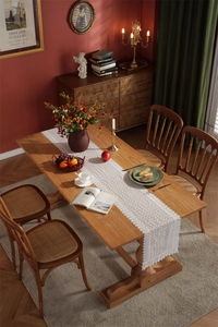 Detailed macro view of white floral hollow lace table runner on a wooden dining table