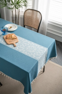 Close-up of blue jacquard tablecloth with white floral pattern and fringe edge