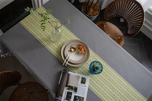 Close-up of grey jacquard tablecloth featuring bohemian fringe and geometric pattern