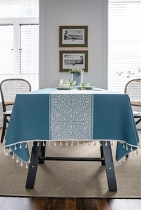 Macro detail of navy blue tablecloth featuring white geometric patterns and tassel edges