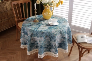 Detail of vintage blue jacquard tablecloth with white daisy pattern and cream fringe edges