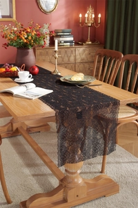 Macro detail of high-density black lace table runner with intricate rose floral patterns