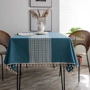Blue geometric jacquard tablecloth with white tassels in a minimalist home setting
