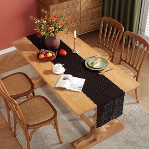 Elegant black lace table runner with hollow floral patterns on a rustic wooden dining table