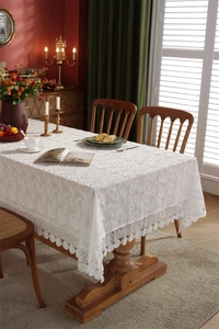Close-up of white French lace tablecloth with 3D floral embroidery and ball fringe