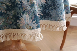 Close-up of vintage blue daisy jacquard fabric and delicate fringe tassels on the tablecloth
