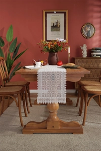 Detail of white crochet lace table runner with hollow floral pattern and fringe edges
