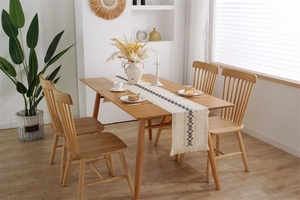 Détail d'un chemin de table bohème en lin crème avec motifs géométriques et franges