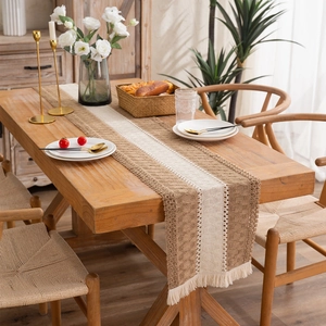 Bohemian woven table runner with coffee and beige fringe on a rustic wooden dining table