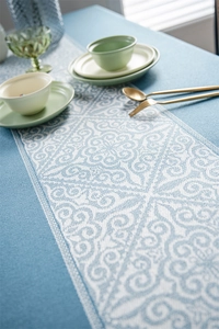 Detail of blue jacquard tablecloth with geometric white lace patterns and textured weave